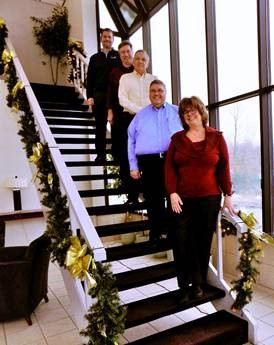 A portrait of the company officers at Trans Overseas, taken on a stair case. At the bottom is Maryann Underhill, then Paul Avery, Tom Ward, Joe Kamykowski, and Brett Ouellette.